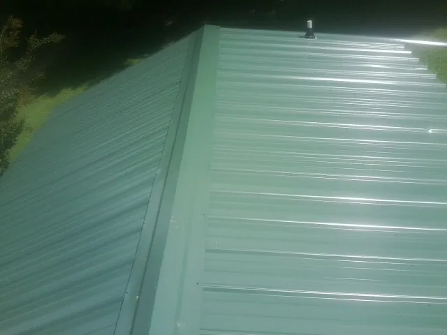 New green metal panels meeting at the ridge of a roof — Flat Roof Repair work by our crew in Vienna
