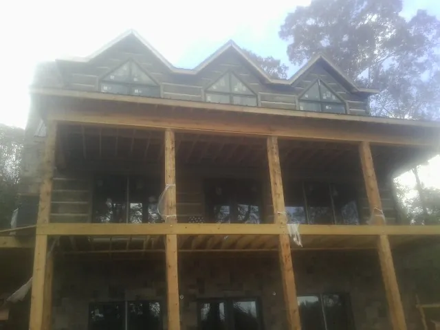 Dormers and porch framing on a large log home under construction — Roof Coating work by our crew in Vienna